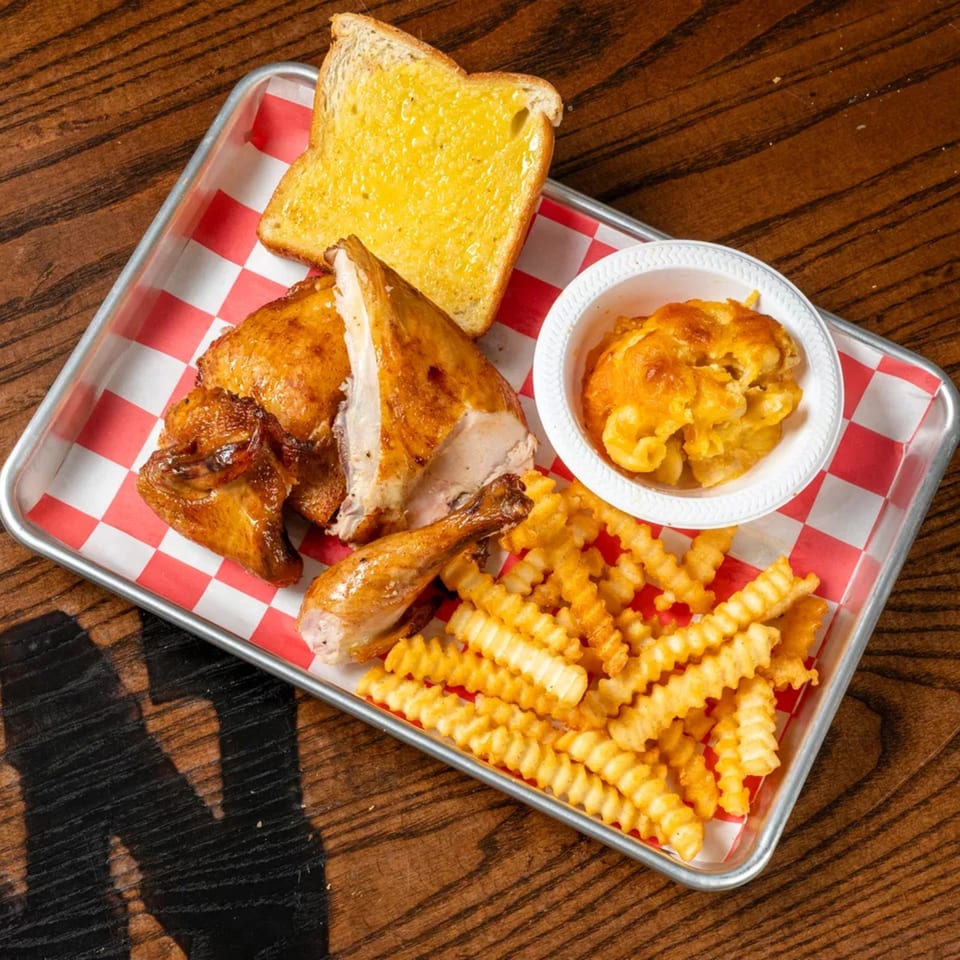 Roasted chicken, crinkle-cut fries, mac and cheese, and Texas toast on a red checkered tray.