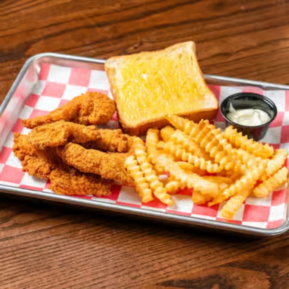 Fried chicken tenders, crinkle-cut fries, Texas toast, and dipping sauce on a checkered tray.