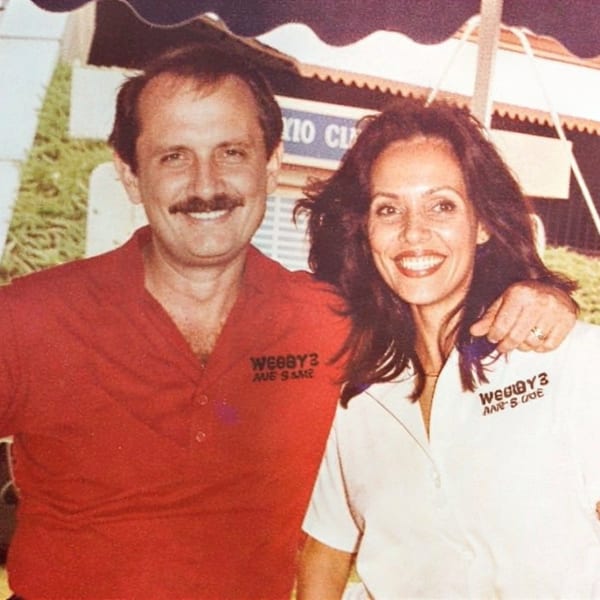 A smiling man in a red shirt with a woman in a white shirt, both wearing "Webby's" shirts.